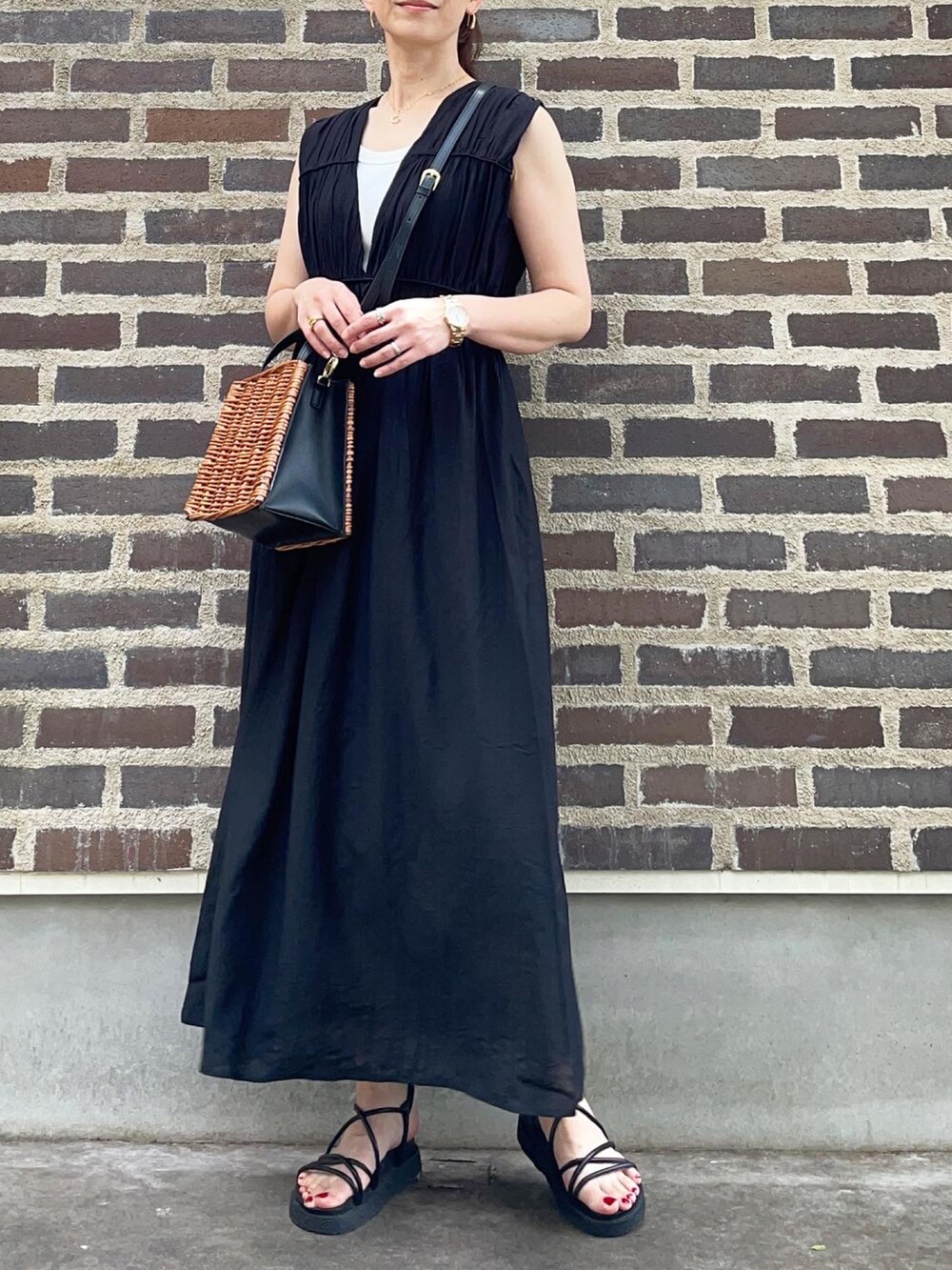 ブラック系のワンピース、ブラック系のサンダル、ブラウン系のかごバッグを着用したレディースの夏コーディネートの2枚目の写真
