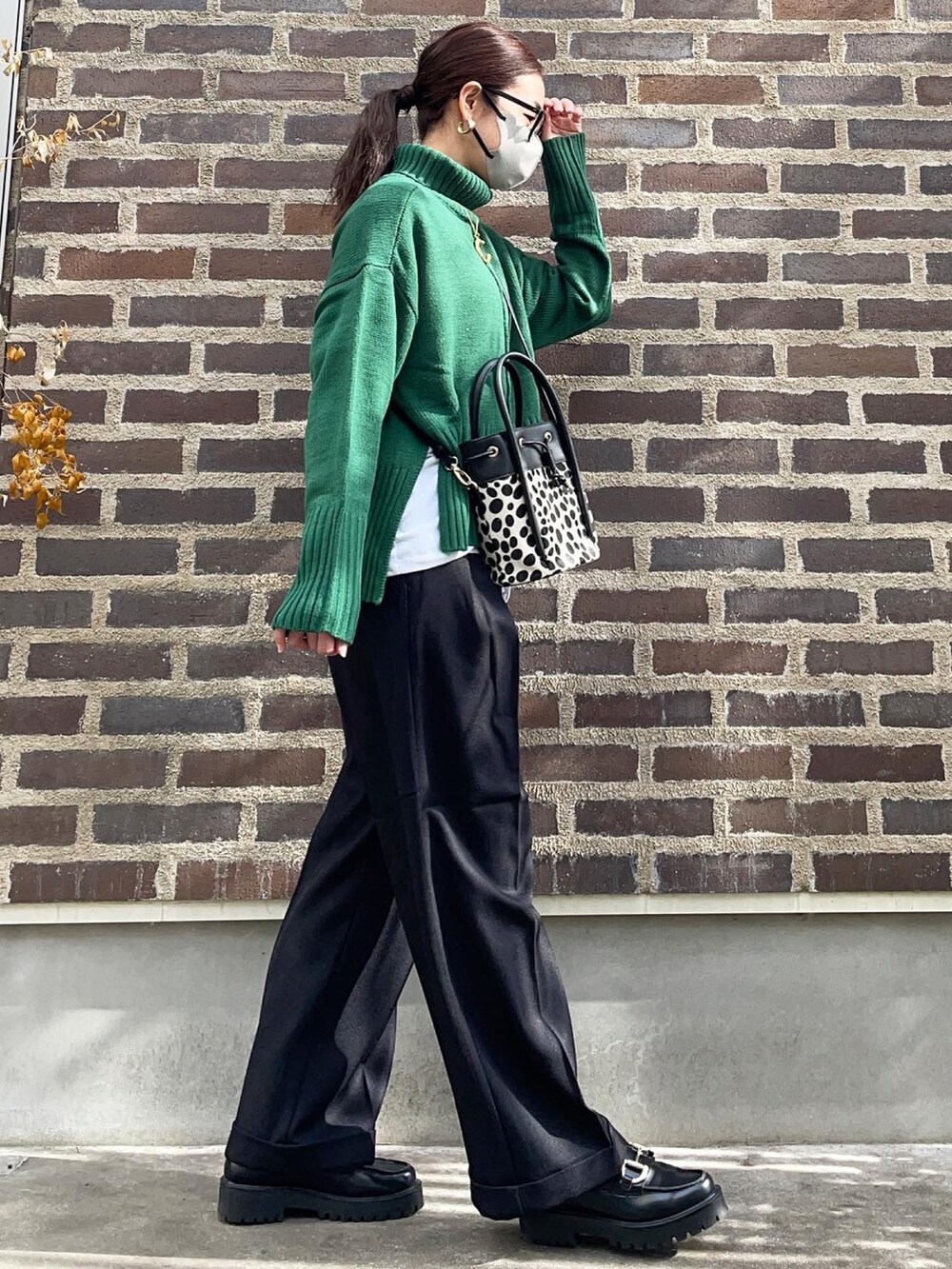 グリーン系のニット/セーター、ブラック系のその他パンツ、ブラック系のローファーを着用したレディースの秋コーディネートの3枚目の写真