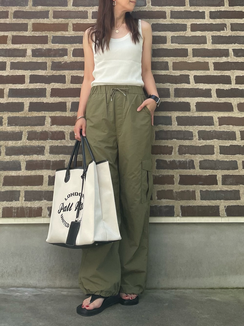 グリーン系のカーゴパンツ、ブラック系のバッグ、ブラック系のサンダルを着用したレディースの夏コーディネートの2枚目の写真