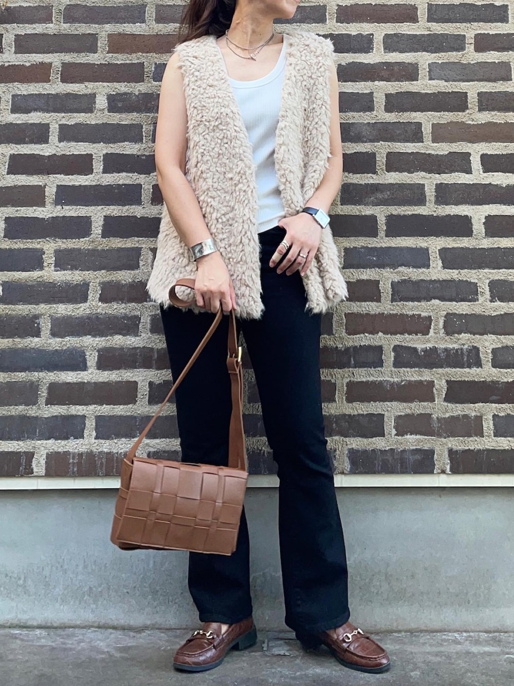 ブラック系のデニムパンツ、ブラウン系のローファー、ブラウン系のショルダーバッグを着用したレディースの秋コーディネートの4枚目の写真