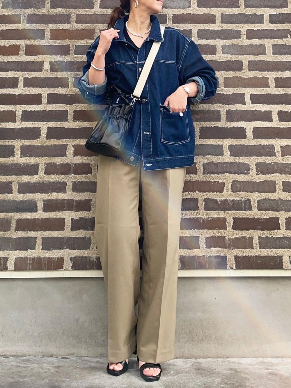 ブルー系のデニムジャケット、ベージュ系のパンツ、ブラック系のサンダルを着用したレディースの冬コーディネートの4枚目の写真