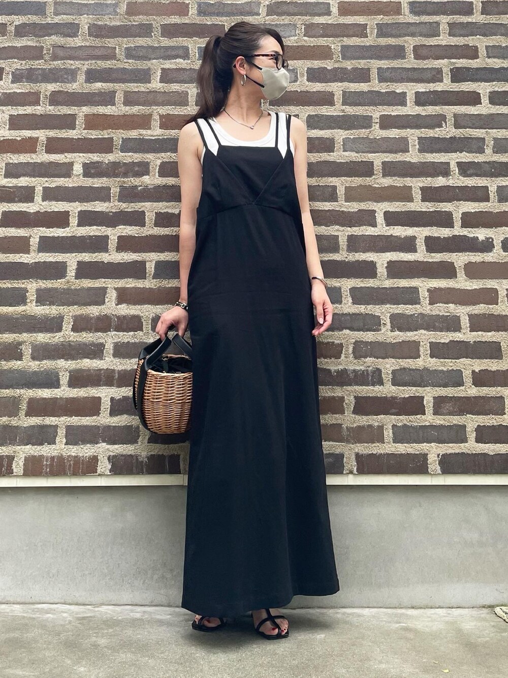 ベージュ系のかごバッグ、ブラック系のサンダル、ブラック系のワンピースを着用したレディースの春コーディネートの3枚目の写真