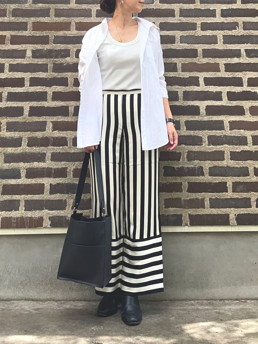 ブラック系のその他パンツ、ブラック系のブーツ、シルバー系のアナログ腕時計を着用したレディースの秋コーディネートの2枚目の写真