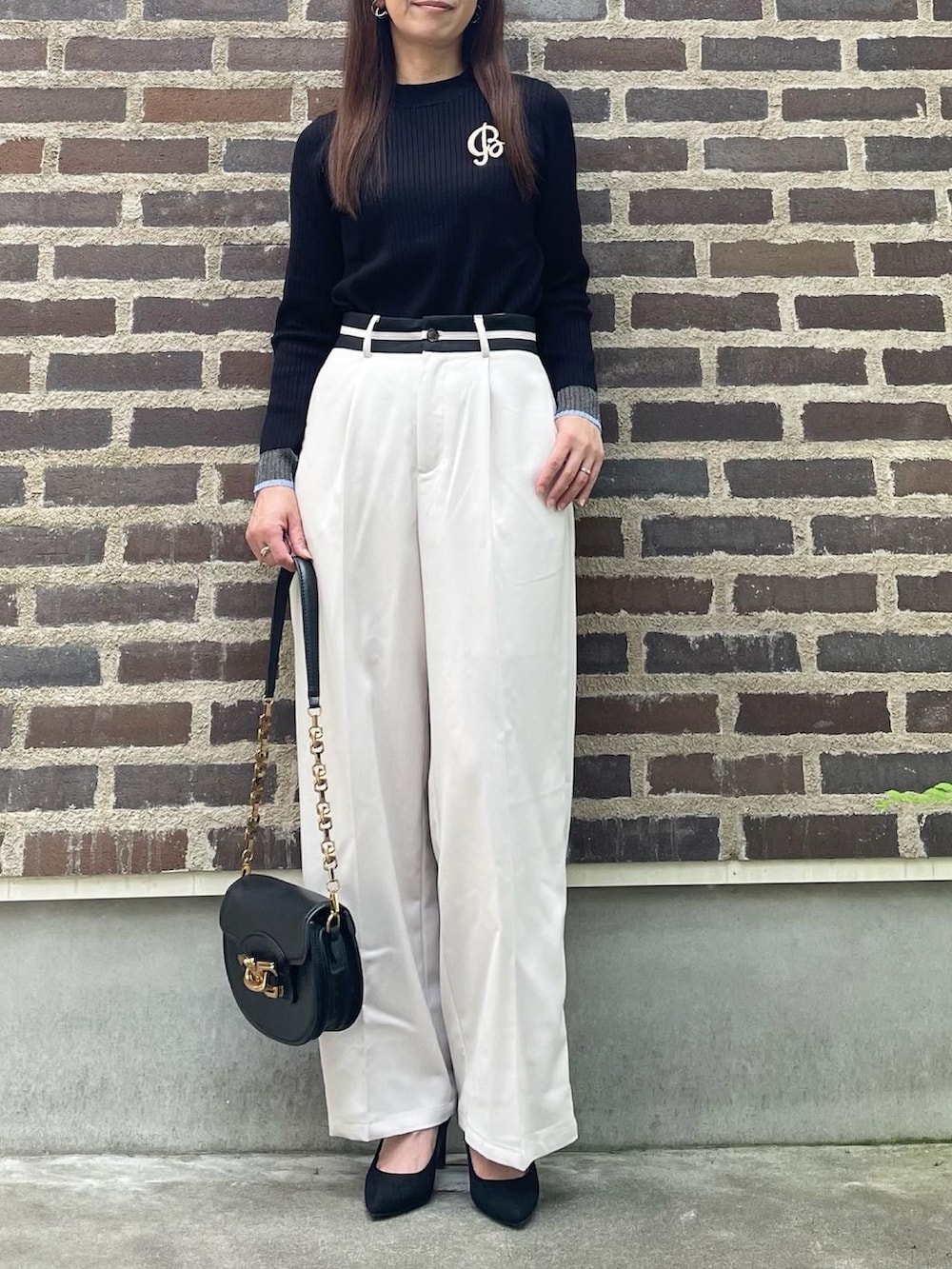 ブラック系のニット/セーター、ホワイト系のスラックス、ブラック系のパンプスを着用したレディースの秋コーディネートの2枚目の写真