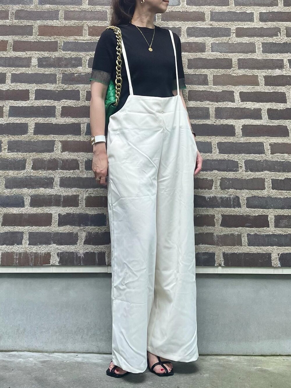 ブラック系のニット/セーター、ホワイト系のサロペット/オーバーオール、ブラック系のサンダルを着用したレディースの夏コーディネートの2枚目の写真