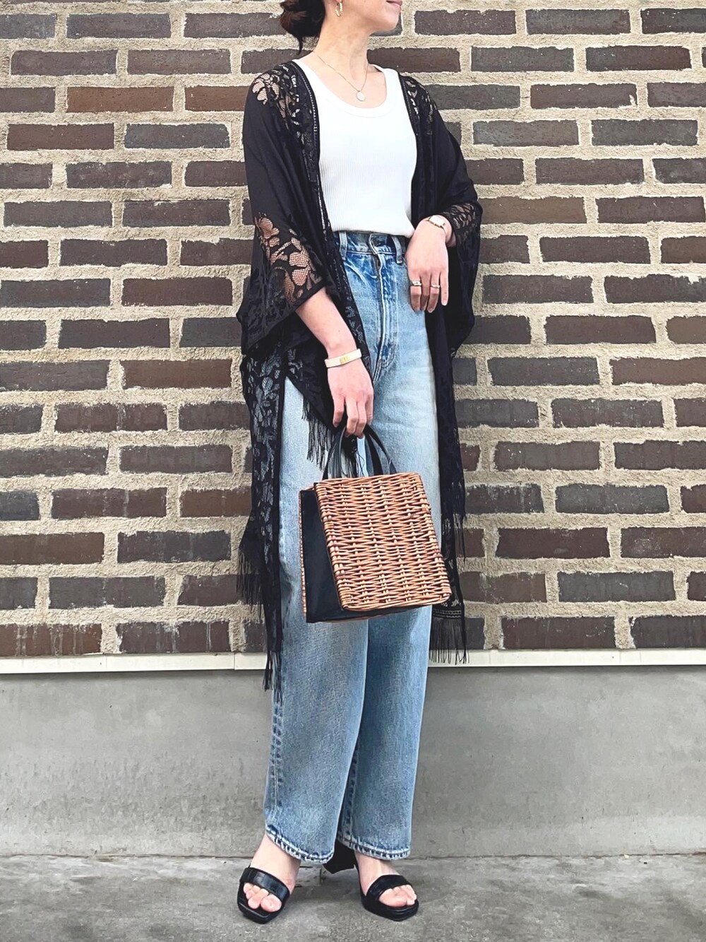 ホワイト系のタンクトップ、ブラック系のポンチョ、ブルー系のデニムパンツを着用したレディースの春コーディネートの2枚目の写真