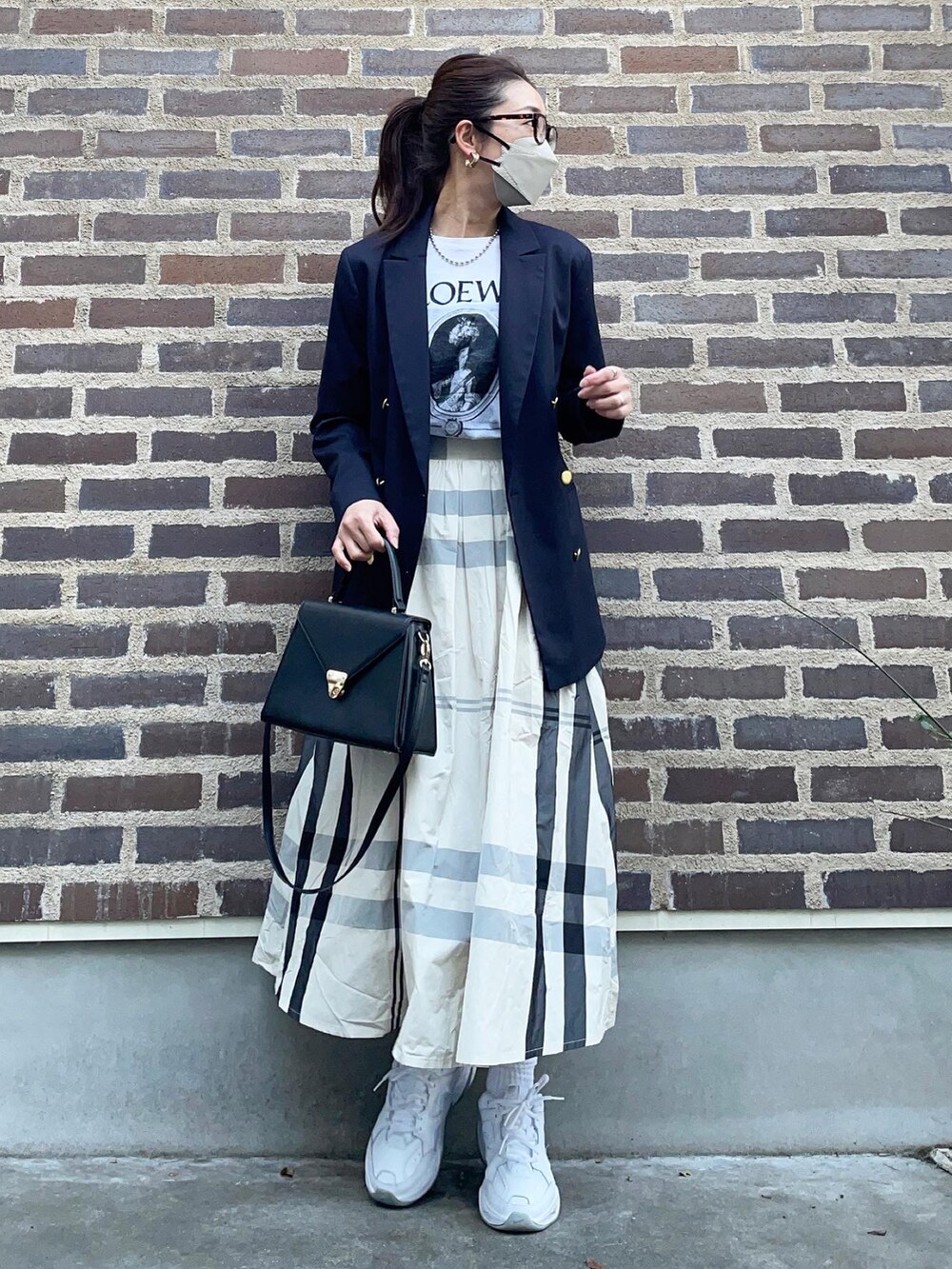 ホワイト系のスカート、ホワイト系のスニーカー、ブルー系のテーラードジャケットを着用したレディースの春コーディネートの3枚目の写真